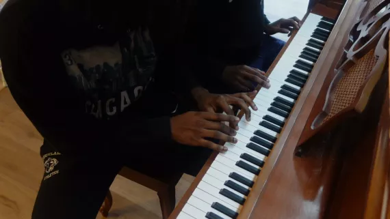 BYMOC Initiative attendees at the Y at Watson Woods learning to play the piano.