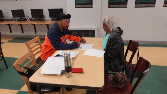 Emma Kimble (right) talking with a VITA staff during the CASH tax services program at the Thurston Road YMCA Neighborhood Center.