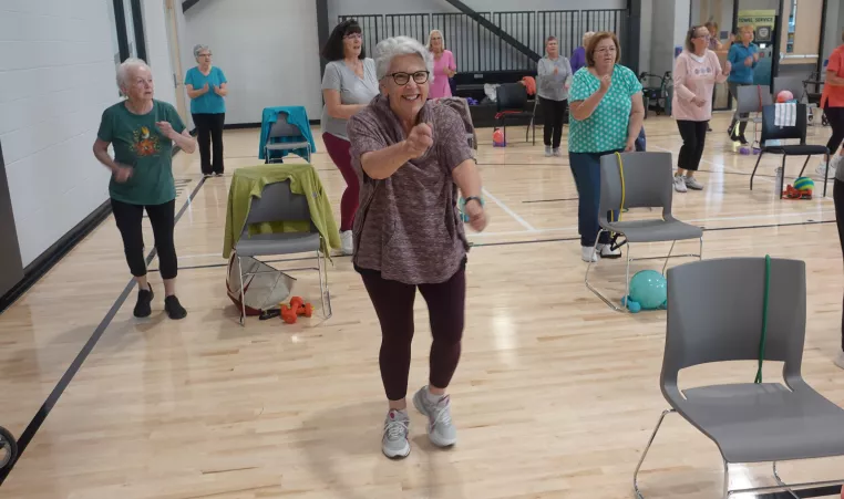 active older adult in a silver sneakers class moving and smiling towards camera