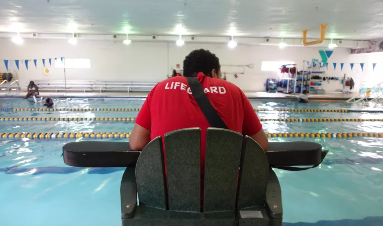 ymca lifeguard sits at stand while on duty keeping water safe
