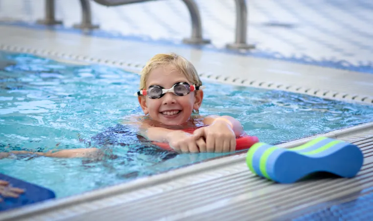 Child wearing goggles swimming in the pool