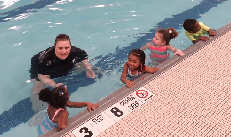 lifeguard teaching kids in the pool