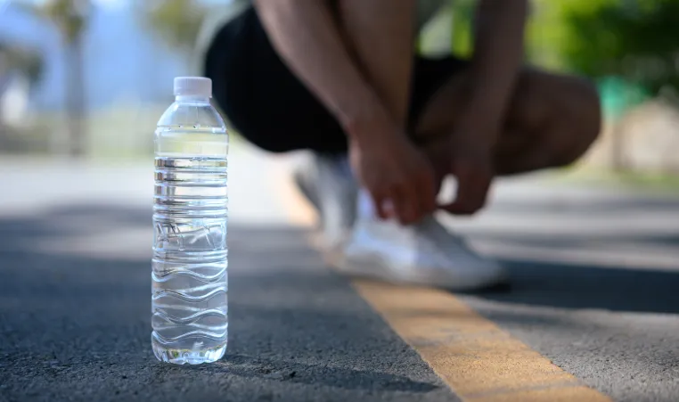 Person tying shoes next to water bottle