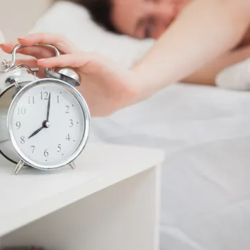 person turning off their alarm clock in bed