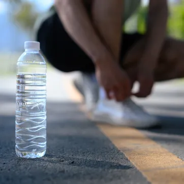 Person tying shoes next to water bottle