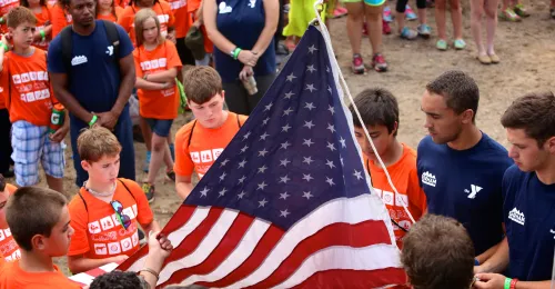 Group of campers and staff folding an American Flag