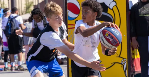 two youth competing with a basketball in their hands