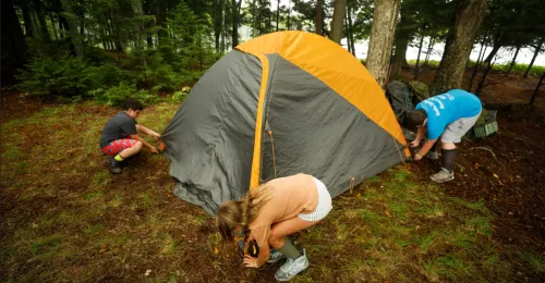 campers setting up a tent in the woods