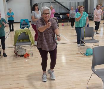 active older adult in a silver sneakers class moving and smiling towards camera