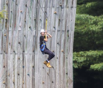 a camper glides down the zipline with a big smile