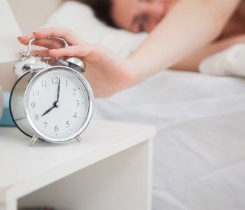 person turning off their alarm clock in bed