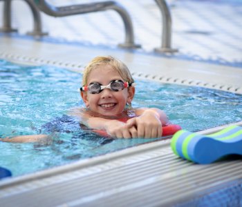 Child wearing goggles swimming in the pool