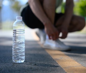 Person tying shoes next to water bottle